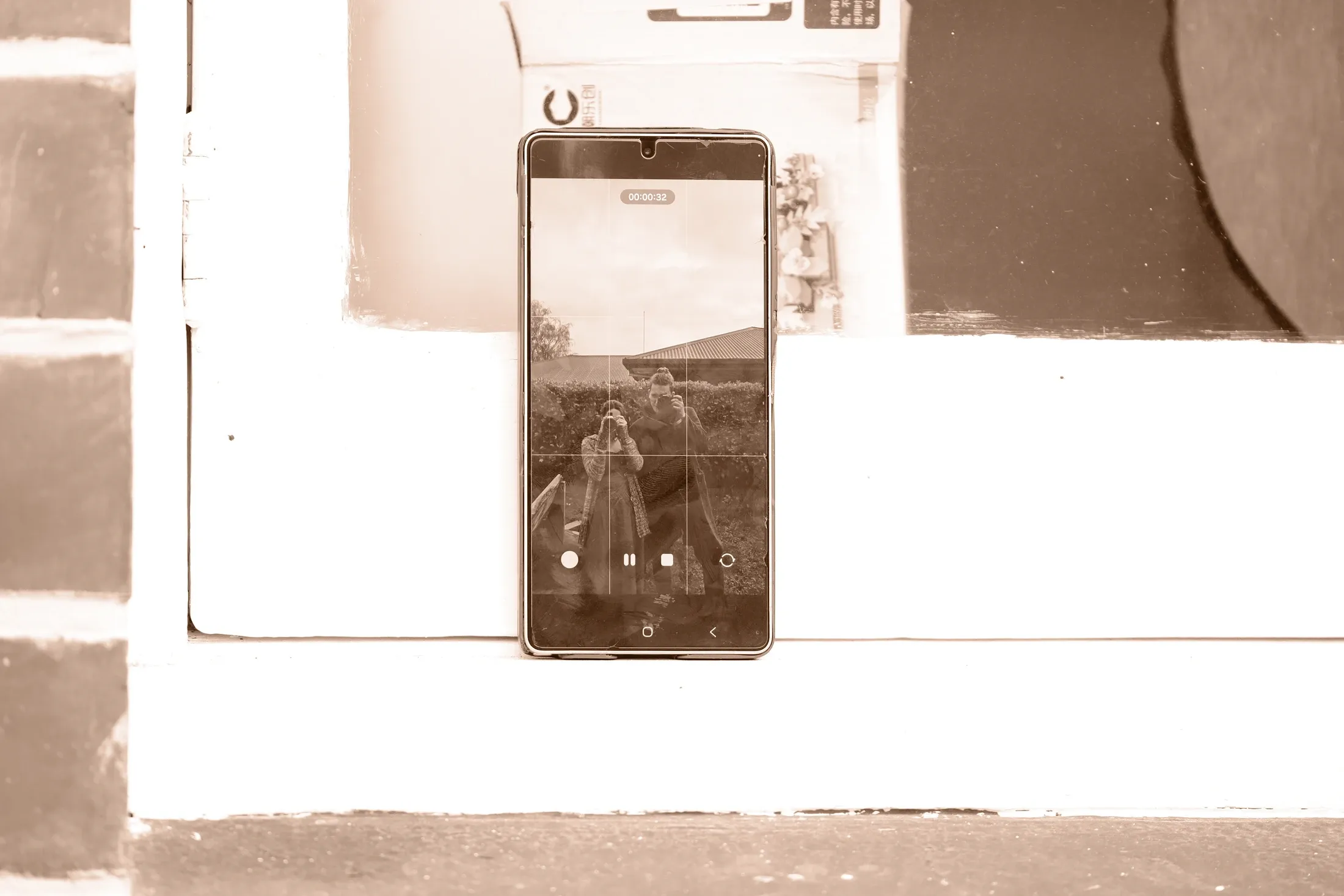 Kenan and Caitlin appear together in a phone screen and reflection