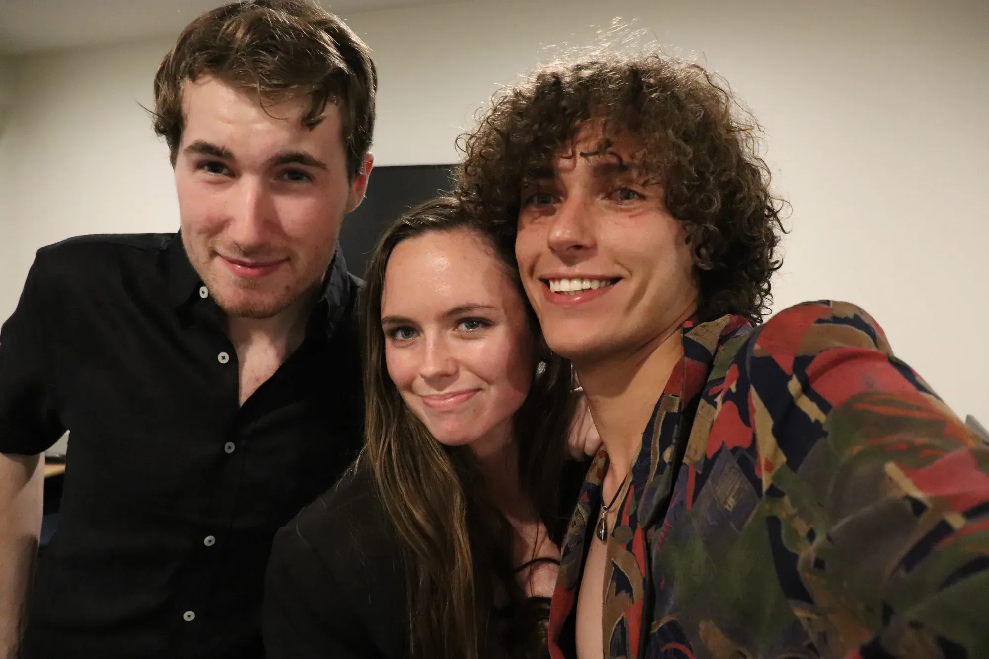 Three friends gather closely for an indoor portrait